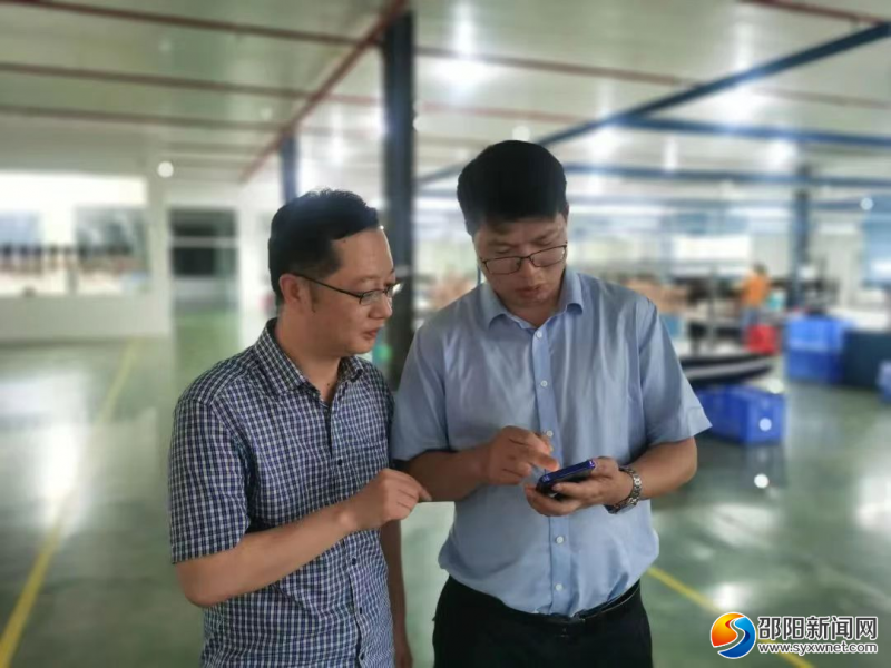 邵阳经济技术开发区联企干部（左)指导企业负责人查阅“惠企政策口袋书”